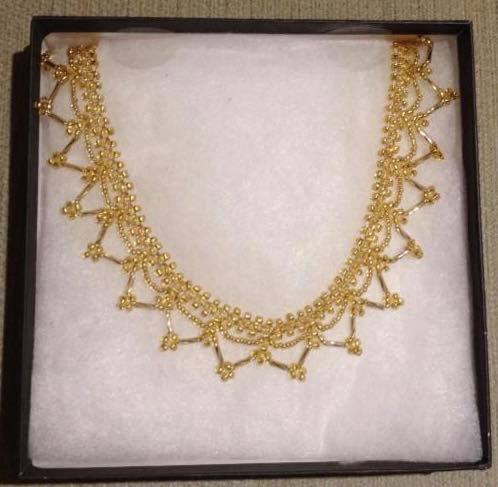 Gold lace necklace in a gift box with white wadding.