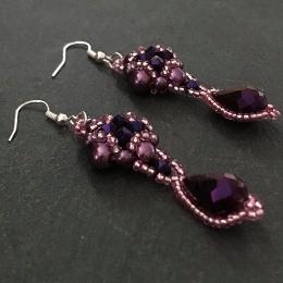 Dark purple Hulton Abbey earrings lying diagonally on a grey slate.