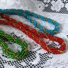 Three spiral ropes in green, red and turquoise on a white lace tablecloth.