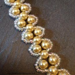 Close up of gold pearl Lady Evelyn bracelet lying on a grey slate.