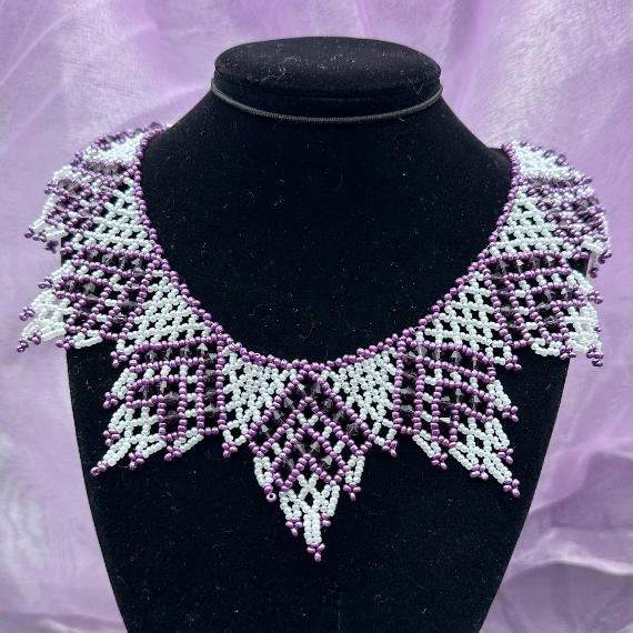 A photo of a lace collar necklace on a velvet stand with a white lace background.