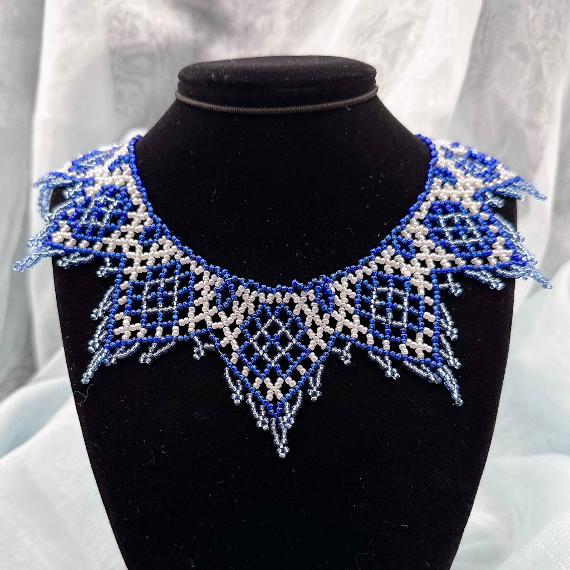 A photo of a lace collar necklace on a velvet stand with a white lace background.