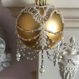 Ivory and silver swags and tails bauble cover on a matt gold ball ornament.