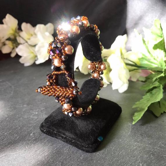 Hulton Abbey bracelet shown on a bracelet stand with some flowers. This lovely bracelet is made from pearls and crystals and has a decoratibve toggle clasp handmade entirely from beads.