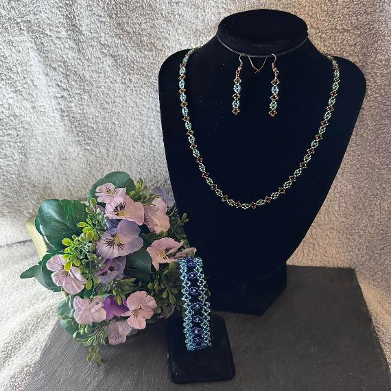 A photo of a blue seed bead bracelet with a matching necklace and earrings.