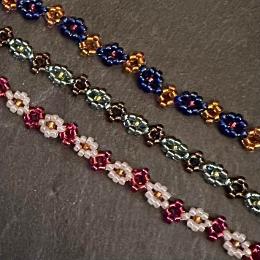 A close up photo of three beaded daisy chains.