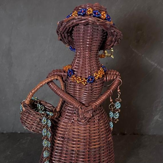 A wicker doll covered in beaded daisy chains.