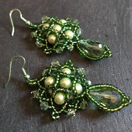 Demeter earrings made form green pearl and crystals and pictures lying down on a grey slate.