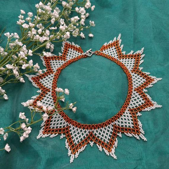 A photo of a lace collar necklace on a velvet stand with a white lace background.