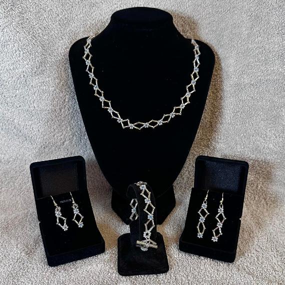 A necklace, bracelet, and two pairs of earrings made from beads on velvet display stands.