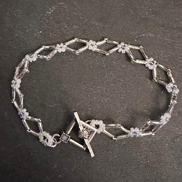 A daisy bracelet with a toggle clasp lying on a grey slate.