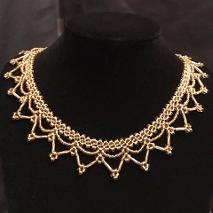 Gold lace handmade necklace on a black velvet stand.