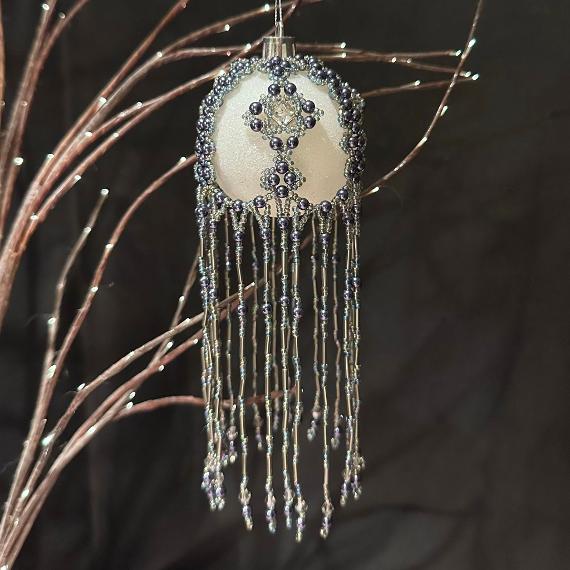 Grey pearl beads on a white bauble Christmas tree ornament.