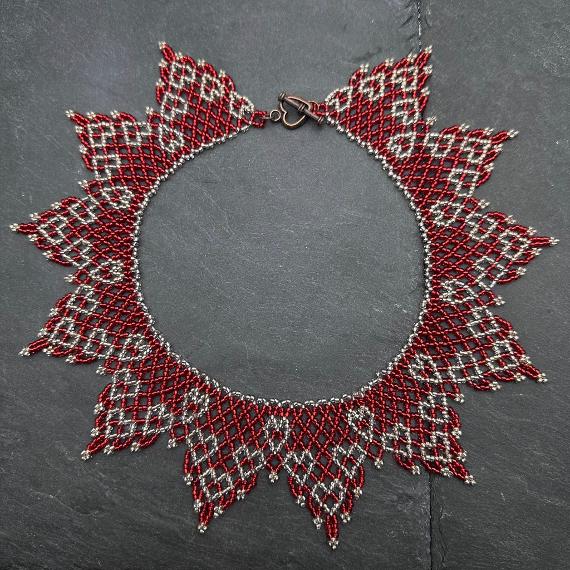 A photo of a lace collar necklace on a velvet stand with a white lace background.