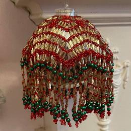 Lumiere bauble made from red seed beads and gold bugle bads with green pearls on a silver Christmas tree bauble.