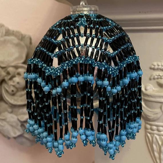 Lumiere bauble made with turquoise and black beads on a silver bauble Christmas tree ornament.