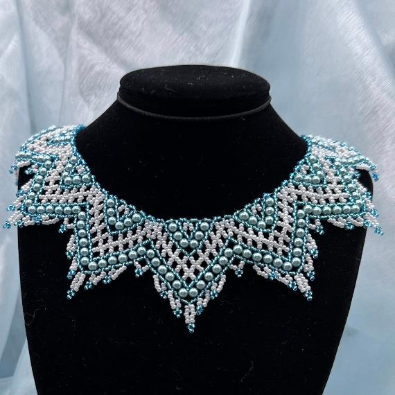 A photo of a lace collar necklace on a velvet stand with a white lace background.