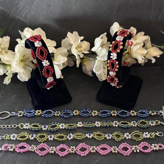 Six bracelets in different colour versions with some white flowers.