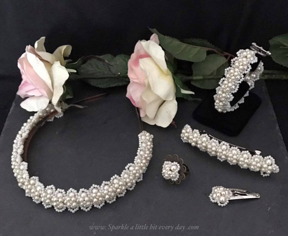 Lady Victoria pattern made using just pearls and turned into hair accessories and a ring, pictured on a grey slate with two roses.