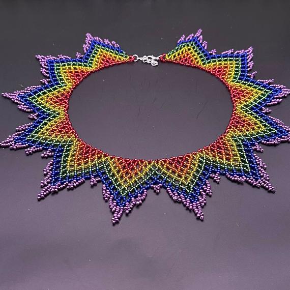 A lace collar necklace made from beads on a velvet stand.