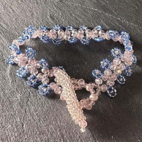 Photo shows a pink and blue crystal bracelet lying on a grey slate.