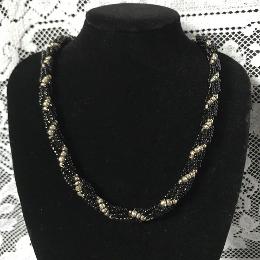 Black and silver spiral rope necklace on a black velvet bust with a white lace background.