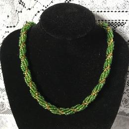 Green seed bead spiral rope necklace on a black velvet display bust in front of a white lace background.