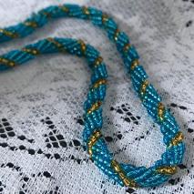 Turquoise and green spiral rope necklace on a white lace tablecloth.