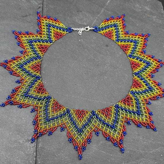 A lace collar necklace made from beads on a velvet stand.