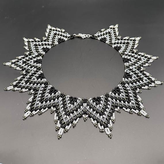 A photo of a black and white lace collar necklace on a velvet stand with a white lace background.