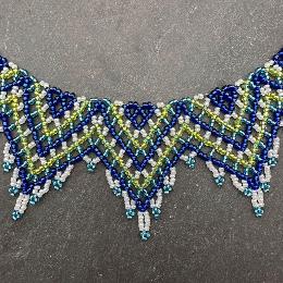 A close up photo of a blue and green beaded collar necklace.