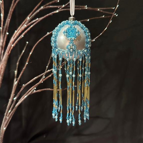 Baroque bauble. Pale turquoise beads hanging from a fibreoptic tree with a black background.