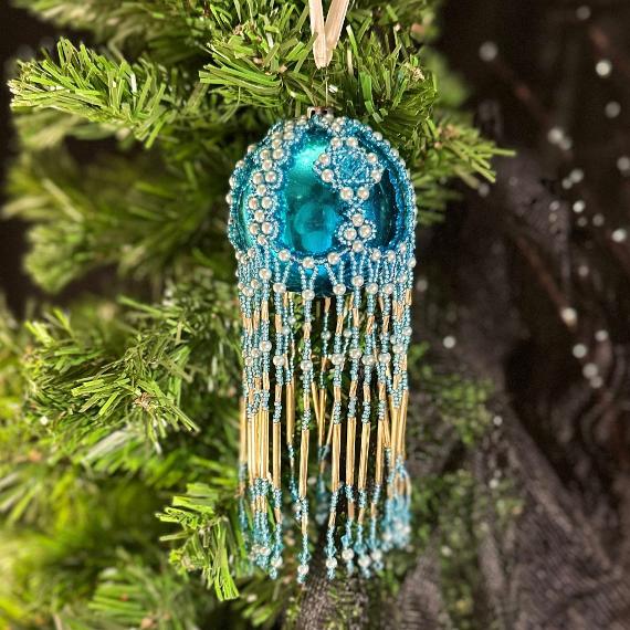 Turquoise bauble in front of a Christmas tree.