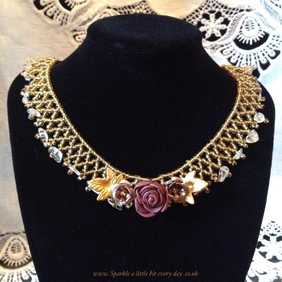 Flower net necklace in shades of gold on a black velvet display bust.